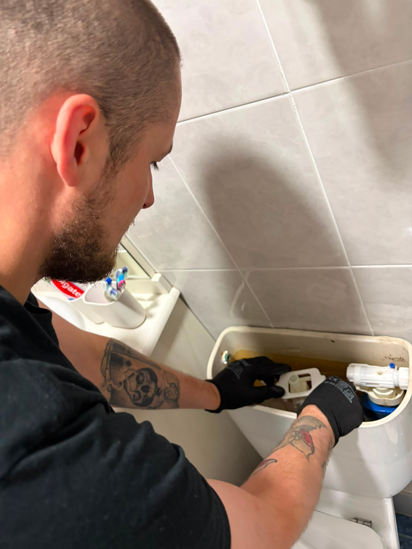 Fontanero reparando el mecanismo interior de una cisterna de inodoro