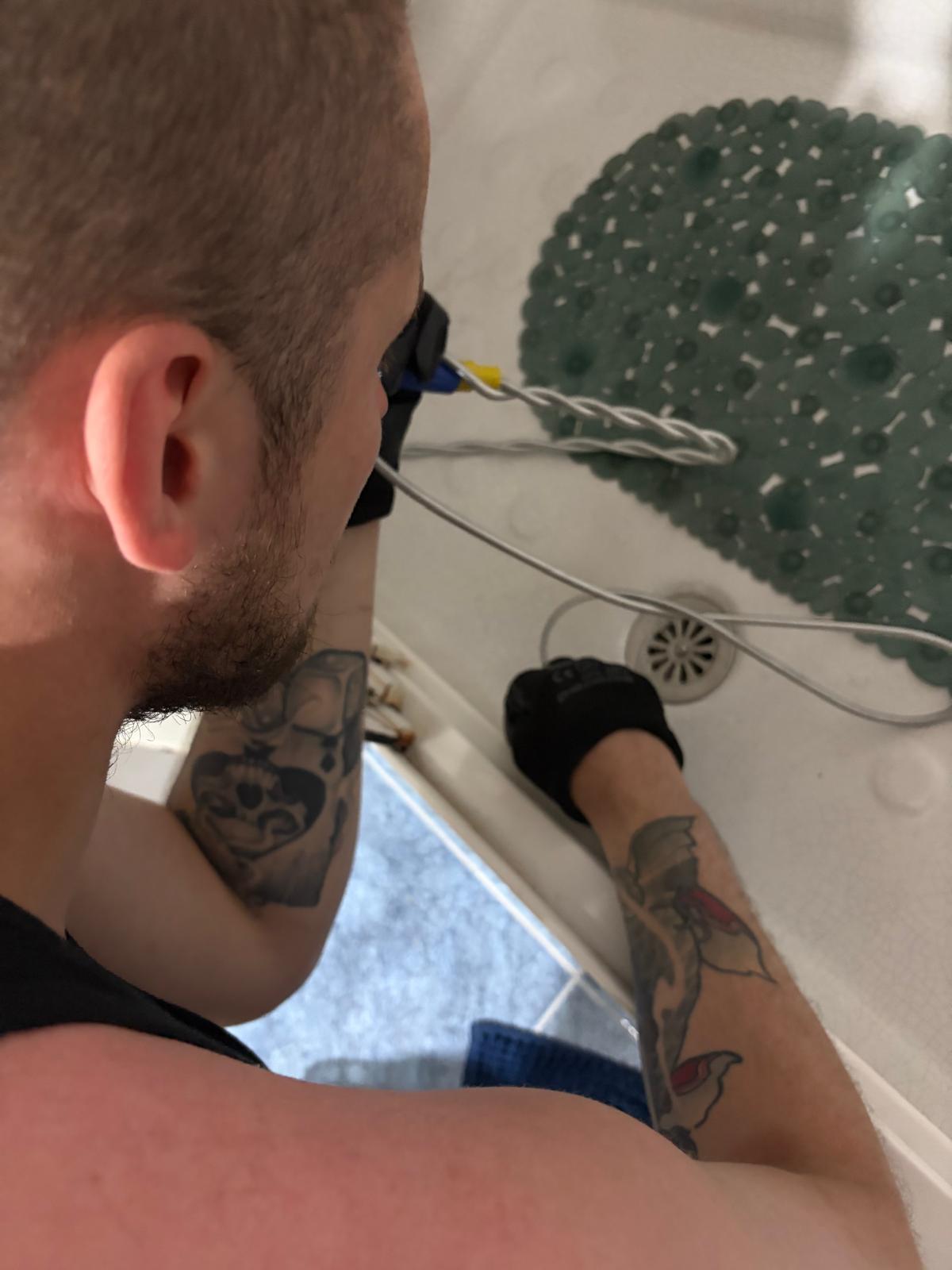 Fontanero desatascando el desagüe de una ducha en Getafe